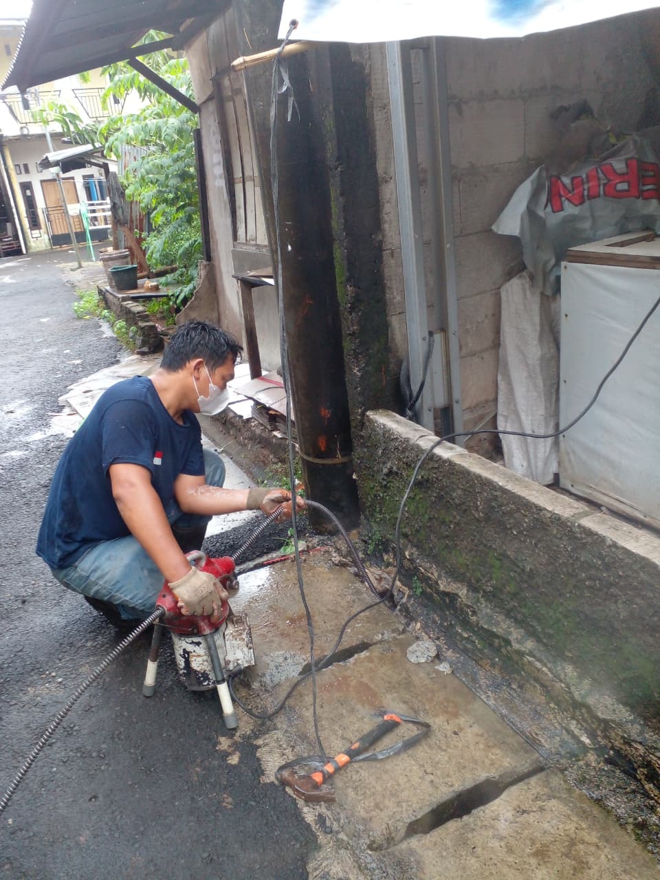 Teknisi Prontech menggunakan mesin pembersih pipa di area kerja luar ruangan.